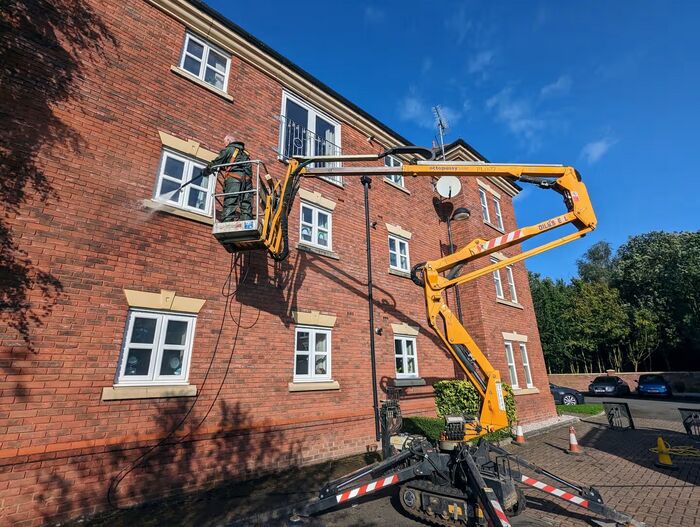 Chris Spruce Cleaning Services cleaning the brickwork of a three-storey building from a cherry picker